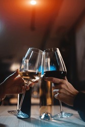two person cheering and celebrate and drink red and white wine in restaurant