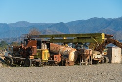 Old abandoned working transport against the background of mountains on a sunny day. Old, rusty working equipment