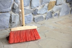 Outdoor red broom for house work on concrete wall background. sweeping the sidewalk