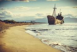 An old abandoned shipwreck, wrecked boat sunken ship stand on beach coast. Scenic seascape