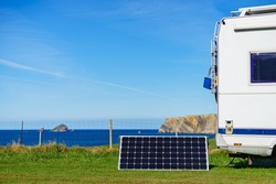 Portable solar photovoltaic panel, charging battery at camper car rv camping on spanish coast.