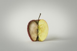 red apple with one half good and the other half rotten, concept of time, fruit that becomes garbage and that is thrown away, white background, isolated object