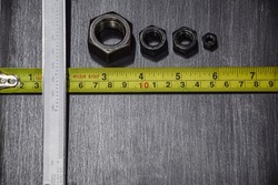 Yellow measuring tape measures the size of a steel plate, textured gray, black pattern, Vernier Caliper, carefully selected bolts, screws, arranged small and large.