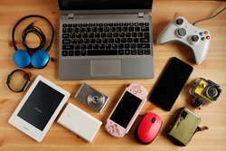 laptop computer with Smartphone and portable game consoles and ebook reader and many electronic gadgets on wooden background.Top view.