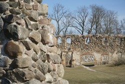 A stone wall of the castle ruins in close-up in view on a background of a historical place from the medieval 14th century. Dobele Castle Ruins in Latvia.