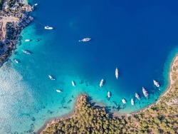 Aerial drone footage of daily tour boats and private yachts anchored in Cennet Bay, located in Selimiye village of Marmaris District of Muğla City, Turkey.