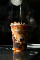 ice latte coffee in plastic glass on black table at cafe​
