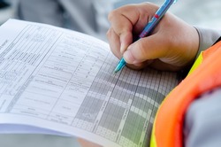 engineer write maintenance inspection check list ,record data for preventive maintenance,hand write data on check sheet. Industrial photo conceptual