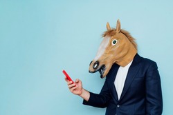 Businessman with horse mask using smartphone