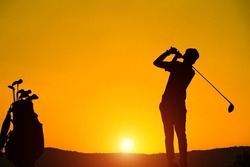 Golfers' hit golf ball toward the hole at sunset silhouetted. Golden morning sky in winter, misty high mountain background.                               
