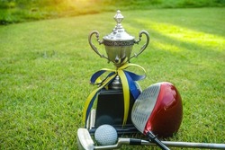 Golf champion trophy on green grass with golf clubs and golf ball in beautiful golf course.                               