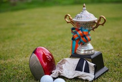 Golf champion trophy on green grass with golf clubs and golf ball in beautiful golf course.                                