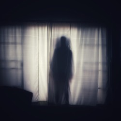The ghost shadow standing behind the door curtain and looked into the room, blurred image.