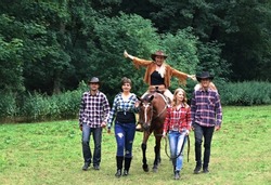 The group of happy smiling people walking with the horse in the nature