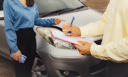 Car insurance claim concept : The victim of a female driver in a traffic accident on a road was describing the scene to an auto insurance agent to properly claim the damage according to the agreement.