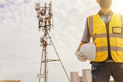 Male technician engineers wearing safety protective clothing work high tower telecommunication antennas installed on buildings for construction, installation and general maintenance work.