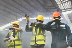 Group of male industrial workers are fleeing and covering their noses with their hands from the toxic fumes of toxic chemicals,ammonia,from violent explosions that make breathing dangerously difficult