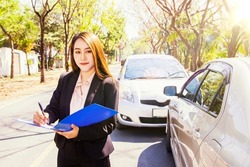 Car insurance business female representative customer service to inspect the area responsible for car insurance during an accident Write down the information to the clipboard : Car insurance concept.