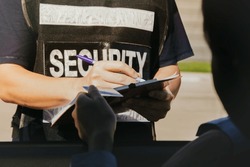 Male security guard records the identity businesswoman who enters the service area submits ID card check for security entry and exit in the area and keeps it as evidence according security measures.