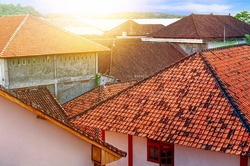 Sunlight from dawn over old houses with tiled roofs. Morning in a small quiet suburb. View from above. City landscape vintage. Asia, Bali.