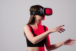 Woman using virtual reality glasses in a studio. Business woman wearing VR goggles and interacts with cyberspace using swipe and stretching gestures.