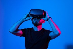 Bearded man in virtual reality headset communicate with a friends in a metaverse. Young man playing a vr video game.