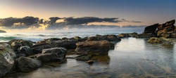 Sunrise seascape panorama with rocks and clouds from Killcare Beach on the Central Coast, NSW, Australia.