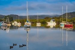 Early morning down by the water with boats, ducks, clouds and reflections at Woy Woy on the Central Coast, NSW, Australia.