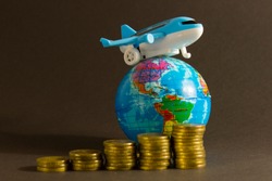 Toy plane on  background of  globe and  coins. Concept of airfare, air travel, air insurance.