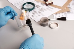 Forensic fingerprint analysis, criminalist collects latent fingerprints using fingerprint powder on evidence -  glass cup