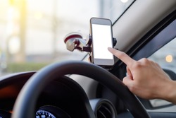 Hand of driver using smartphone which holding on magnet phone mount holder at the car windshield with screen for map GPS navigation on the traffic road background