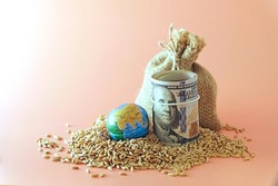 A sack of wheat, spilled, next to a globe, globe and US banknotes. Concept - world food crisis, export, import. The issue of harvest in different countries of the world, the impact of sanctions.