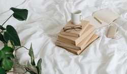 Books and glasses on bed white bed linen. Sweet home morning time. Eco friendly home concept