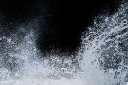 splashing water of sea wave from storm crashing on shore spraying white water foam and bubble in air isolated on black background with clipping path