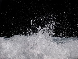 The sea wave crashing on the rock and make the splashing water and white air foam bubble. Isolated on black background with clipping path.