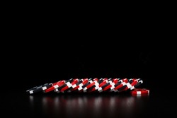 Poker composition of the black and red casino chips lying in line over black background. Isolated objects. Gambling concept