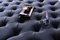 tools on the upholstery of a grey capitoned headboard