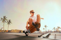 Skateboarder is performing tricks in skatepark on sunset.