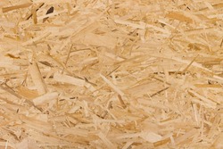Sheet of plywood with fragments of compressed sawdust.OSB boards are made of brown wood chips sanded into a wooden background. Top view of OSB wood veneer background, tight, seamless surfaces.