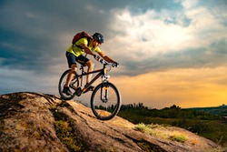 Cyclist Riding the Mountain Bike on the Rocky Trail at Sunset. Extreme Sport and Enduro Biking Concept.