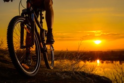 Silhouette of Enduro Cyclist Riding the Mountain Bike on the Rocky Trail at Sunset. Close-up of Bicycle. Active Lifestyle Concept. Free Space for Text.