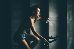 Attractive young woman at the gym riding on spinning bike. Healthy Lifestyle and Sport Concepts. Female after workout session checks results on watch.
