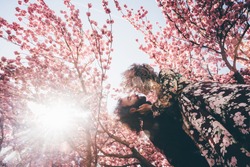 Couple in love enjoying pink cherry blossom. Man and woman in blooming garden.