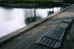 Wooden bench on the shore of the lake. Wooden promenade near the lake in the city park. European parks.