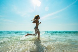 Young woman hight speed running in sea with splashes