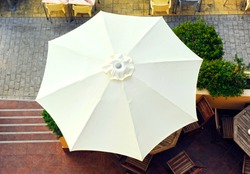 White umbrella seen from above on the terrace of a beach bar