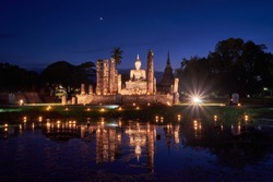 Reflection Twilight and Light up Ancient Ruins of Temple and Buddha Statue with Candle Float in Sukhothai Historic Park, Famous Destination for Loy Krathong Festival, Cultural World Heritage 
