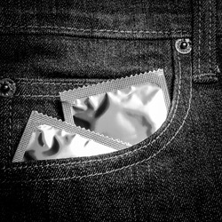 Condoms in pants.Condom in the blue jeans is on the table, Condom in the pocket of a blue jeans - low key for have a dark image.