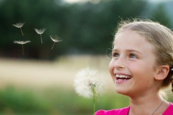 Summer joy - lovely girl blowing dandelion