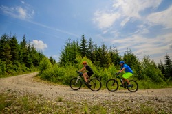 Cycling woman and man at Beskidy mountains forest landscape. Couple riding MTB enduro track. Outdoor sport activity.